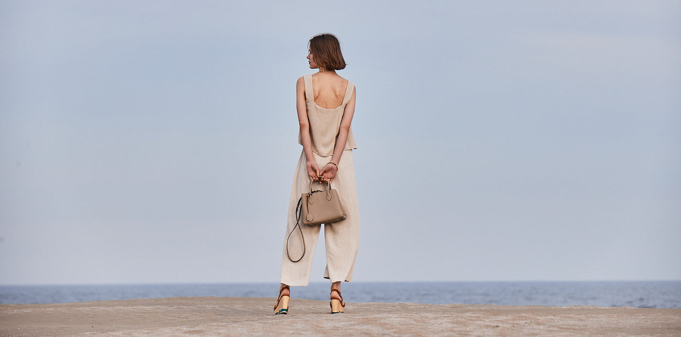 Eine Frau am Strand mit einer nachhaltigen BONAVENTURA Tasche. 