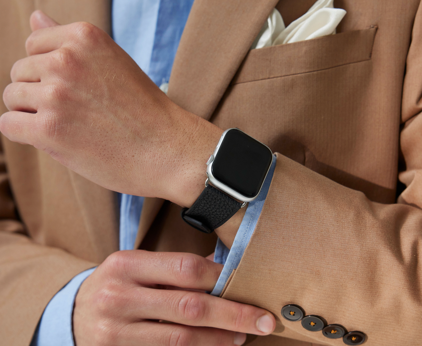 Eleganter Geschäftsmann zeigt sein Apple Watchband aus hochwertigem Leder in einem professionellen Umfeld.